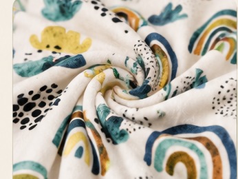 Detalhe da textura macia da manta MimiBaby, tecido enrolado mostrando a estampa e o plush
